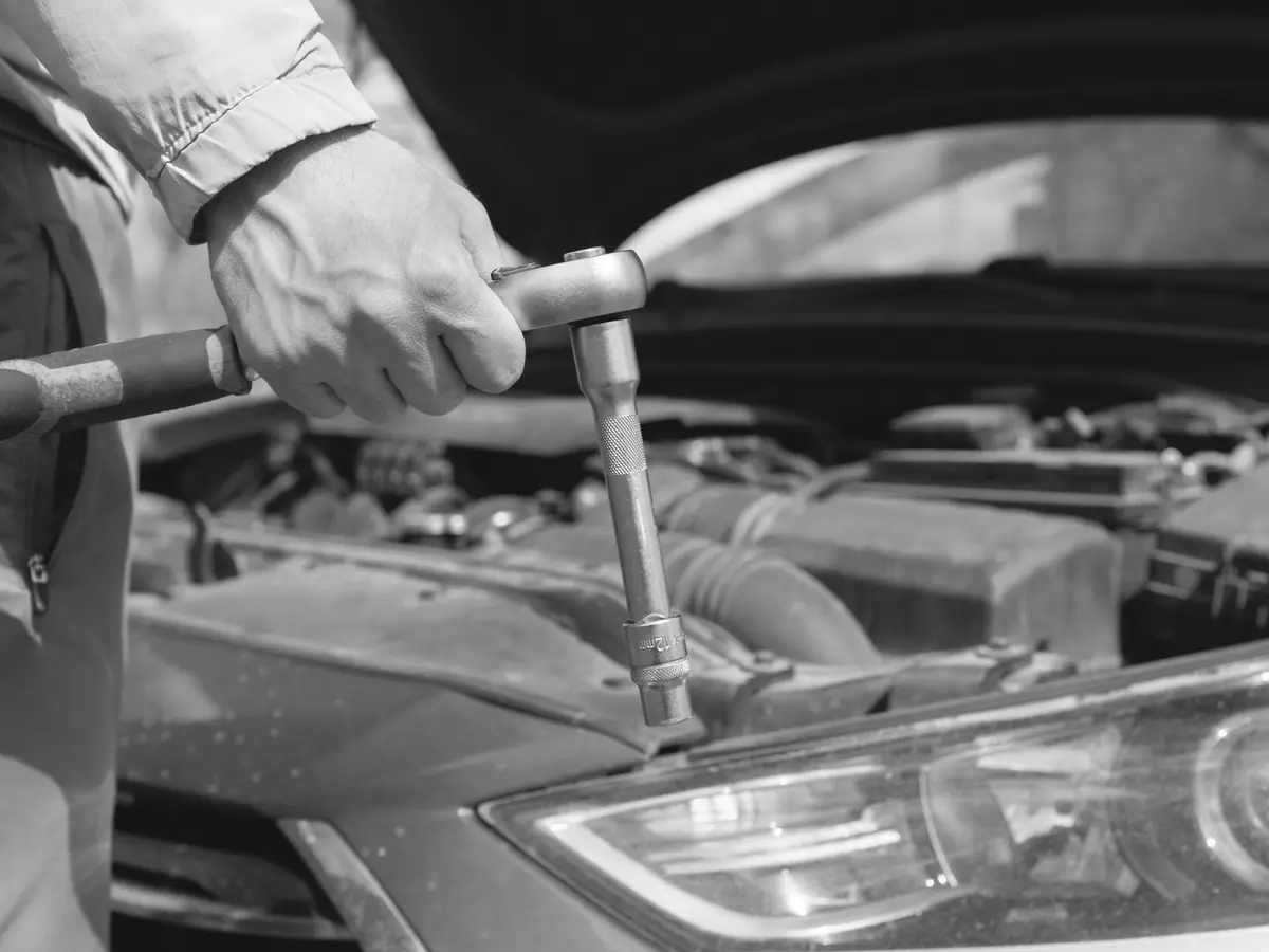 Chave apertando uma peça no motor de um carro.